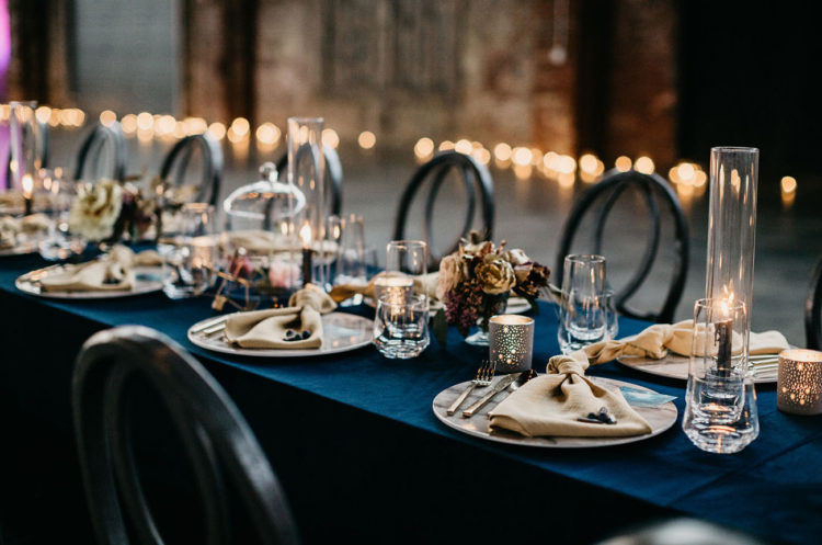 The wedding reception tables were done with navy tablecloths and metallic touches plus dried and moody blooms
