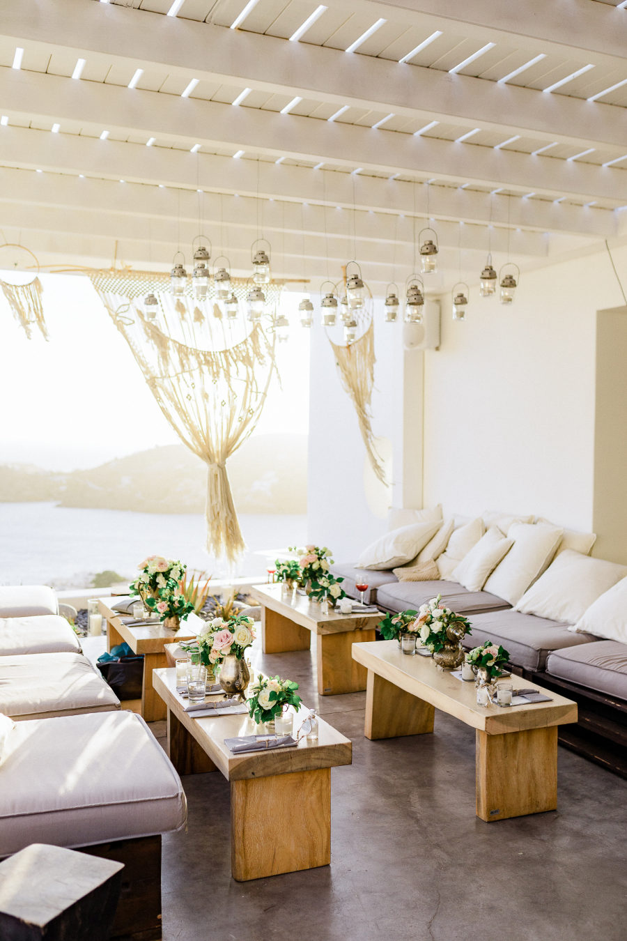 What a beautiful wedding lounge with little tables and upholstered benches with sea views