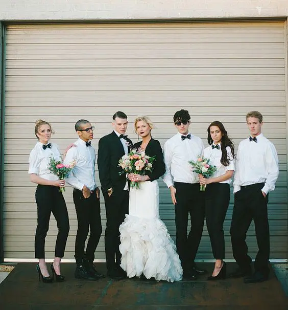 both bridesmaids or groomsladies and groomsmen wearing white shirts, black pants and bow ties and black shoes