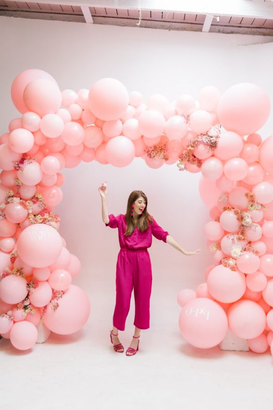 a super cute pink balloon wedding arch with pink and white blooms interwoven is a very cool idea