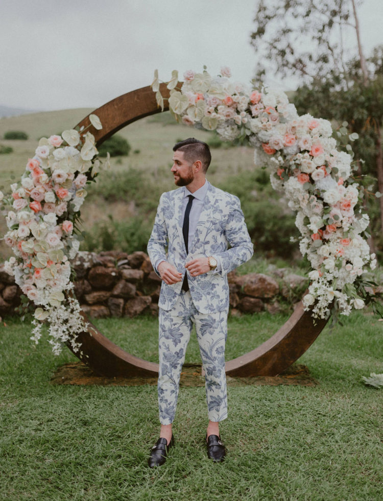 a blue floral print suit, a white shirt, a black tie and black shoes with no socks is a very daring idea
