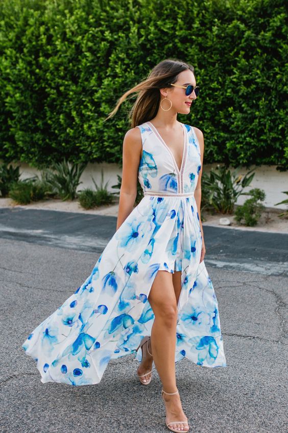 a bright blue floral print jumpsuit with a long skirt over it, a V-neckline and no sleeves plus nude heeled sandals