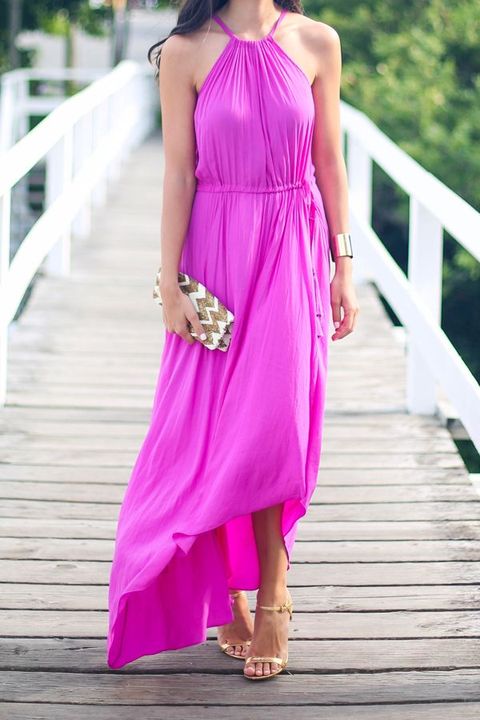 a hot pink maxi dress with an asymmetrical skirt and a halter neckline, a metallic bracelet and shoes