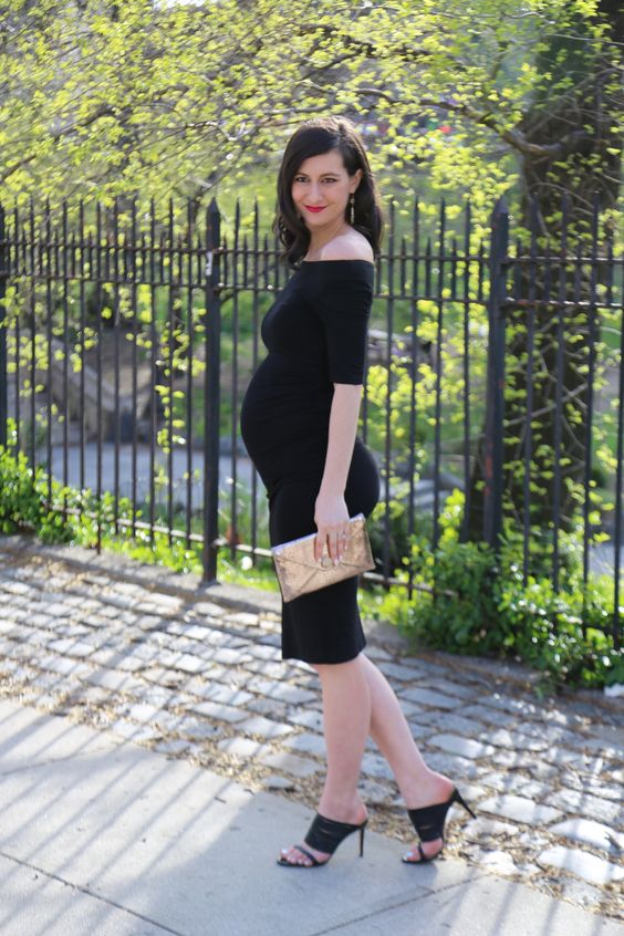 a more formal look with an off the shoulder black knee dress with short sleeves, black heels and a metallic clutch