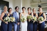 18 a bridesman wearing a light blue suit and girls rocking navy wrap gowns create a harmonious look