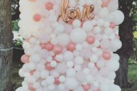 19 a bright and catchy balloon wedding backdrop in peachy and white with a love sign of balloons, too