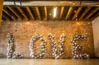 20 a creative wedding backdrop of wire letters filled with grey balloons and greenery interweaving for a modern wedding
