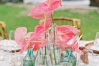 21 a beachy wedding centerpiece of bright pink anthuriums in blue vases and of seashells