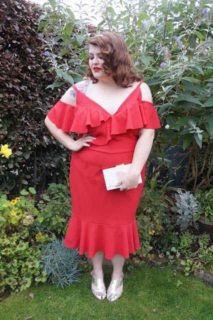 a red midi dress with a ruffled neckline, a cold shoulder, metallic shoes and a small white clutch
