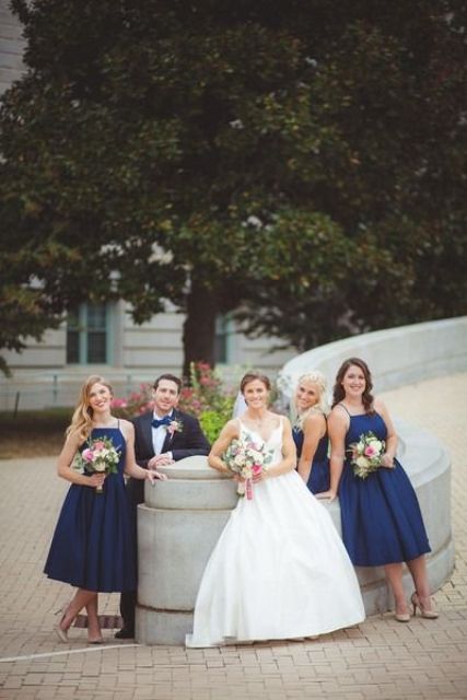 navy midi dresses with halter necklines match a grey suit with a navy bow tie to create an elegant party look