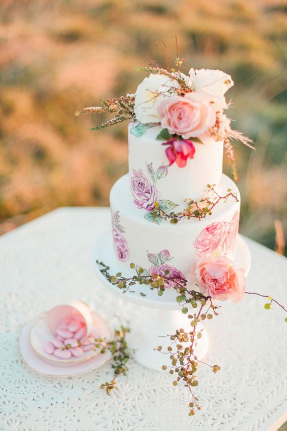 a chic handpainted wedding cake with blooms and greenery and flowers on top for a romantic wedding