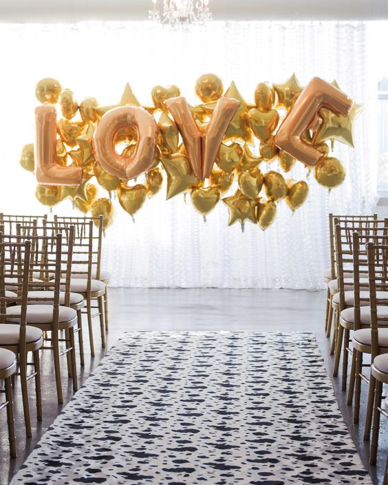 a gold balloon wedding backdrop of LOVE letters and hearts and stars for a modern fun look
