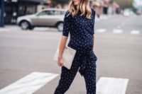 24 a navy printed jumpsuit with cropped pants, a white clutch and red lace up shoes for a more casual feel