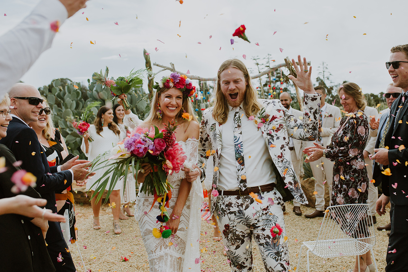 a white floral suit with a bright floral print and a matching tie plus a white shirt for a tropical wedding
