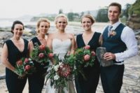 25 bridesmaids wearign black dresses with deep V necklines and a bridesman wearing a black suit with a waistcoat and a floral tie