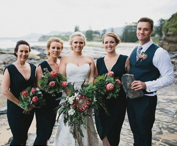 bridesmaids wearign black dresses with deep V necklines and a bridesman wearing a black suit with a waistcoat and a floral tie