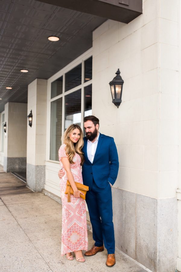 a pink printed maxi dress with short sleeves, nude shoes and a mustard clutch to match his shoes