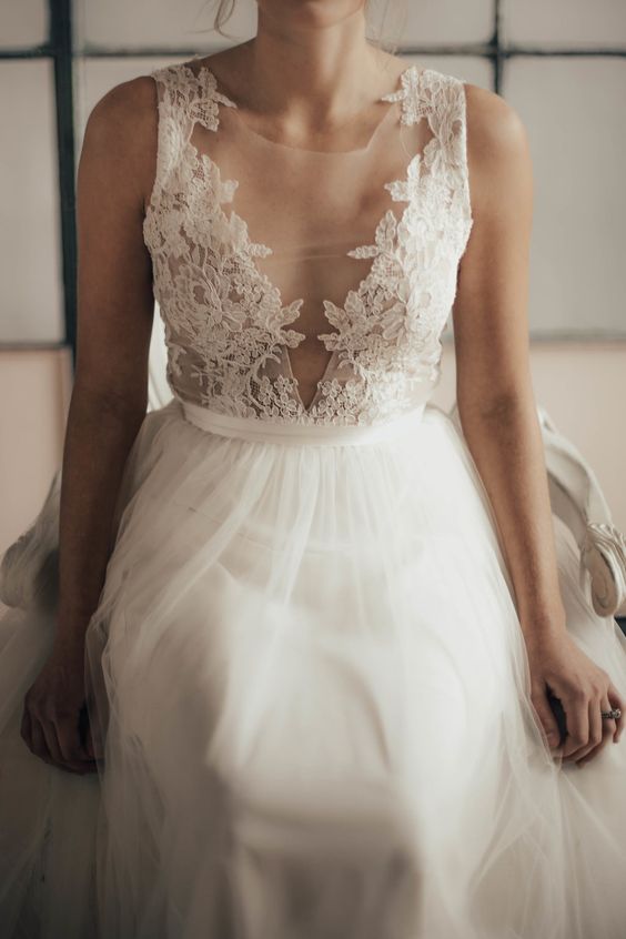 an illusion plunging neckline sleeveless wedding dress with a lace applique bodice and a tulle skirt