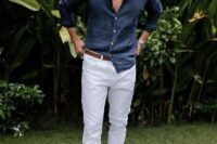 a beach wedding guest outfit with a navy linen shirt, white pants, a brown belt and brown sandals is cool and chic