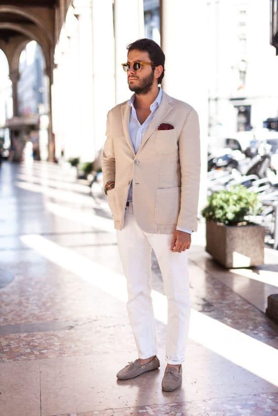 a chic look with a light blue shirt, a tan blazer, white pants, tan leather moccasins and sunglasses