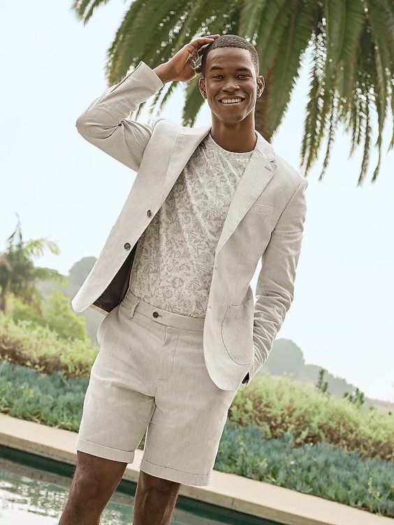 a neutral beacj wedding guest look with a printed t-shirt and a linen suit with shorts