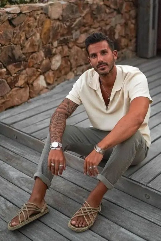 a relaxed and cool boho beach wedding guest look with catchy rope sandals, grey linen pants and a white polo shirt
