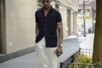a stylish and chic beach wedding guest look with a black short-sleeved shirt, white trousers, tan loafers and sunglasses