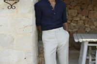 a stylish beach wedding guest outfit with a navy linen shirt, neutral linen pants, printed espadrilles
