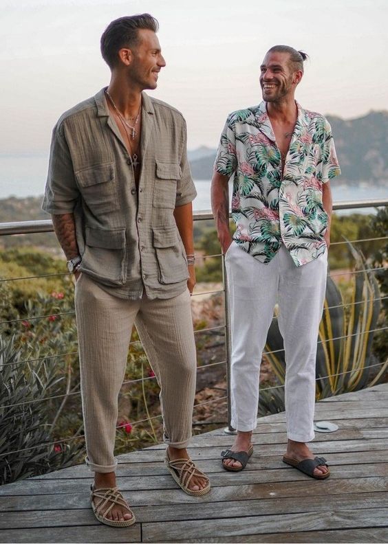 relaxed boho beach wedding guest looks - a grey linen one with rope sandals and a bold tropical print shirt, white linen pants and grey sandals