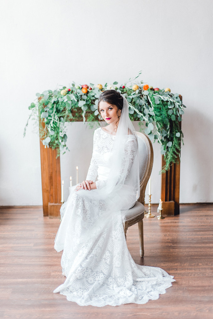 The bride was rocking a bateau neckline lace wedding dress with long sleeves, a plum lip and a wavy updo with a long veil