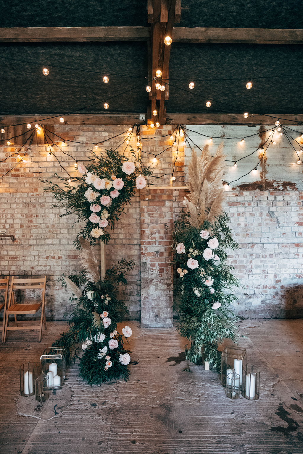 The wedding ceremony space was done with lots of lights, candle lanterns and an arch with lush greenery and blush blooms