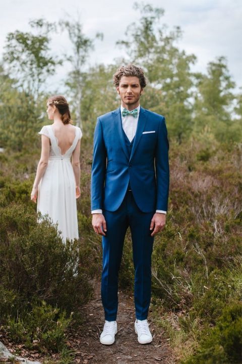 a bold blue three-piece suit, a white shirt, a colorful bow tie and white sneakers for a modern groom's look
