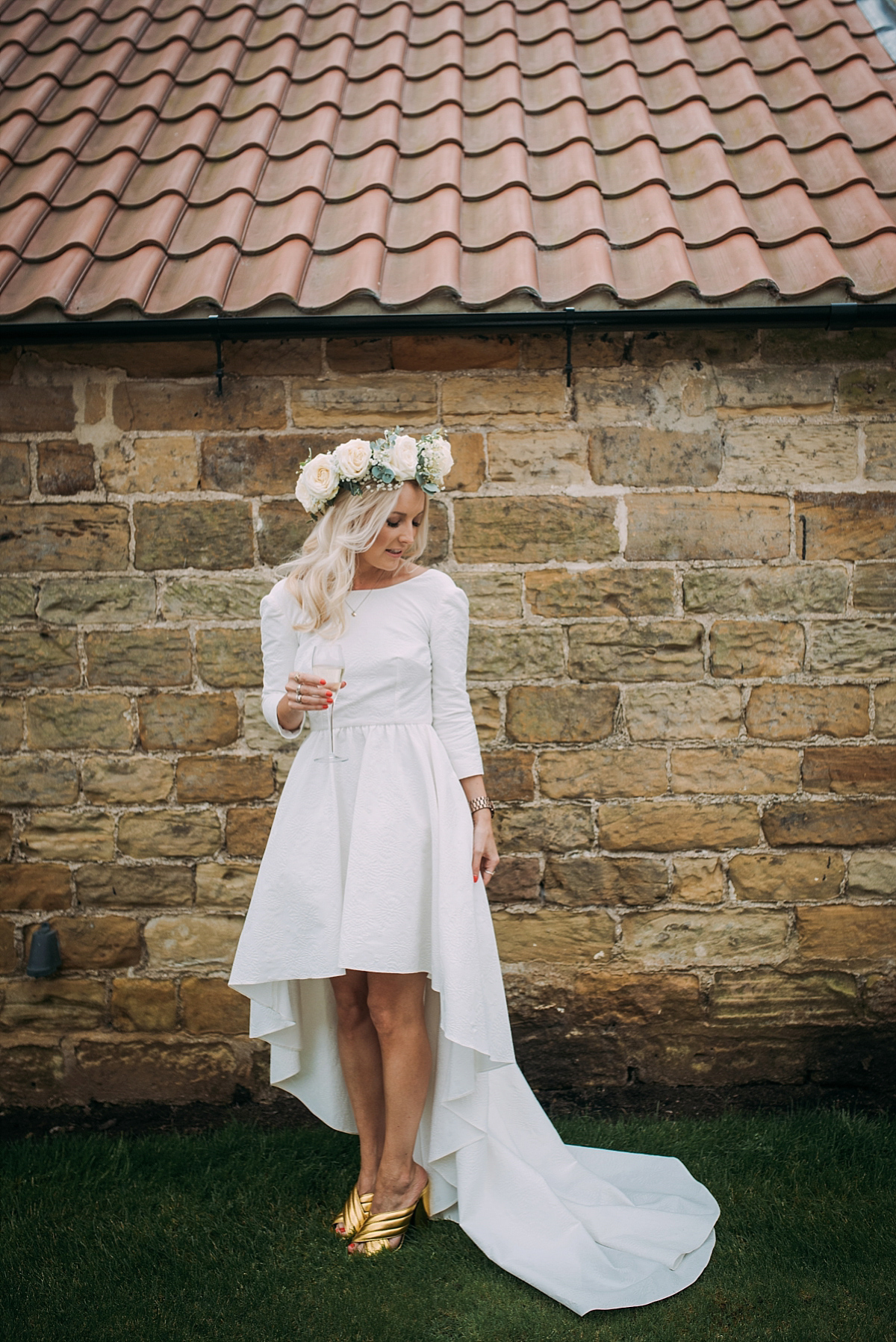 a textural high low wedding dress with long sleeves and a train plus gold mules that add a shiny touch