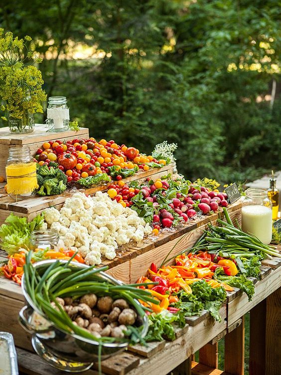 a gorgeous fresh vegetable food bar with various dressings on a wooden display