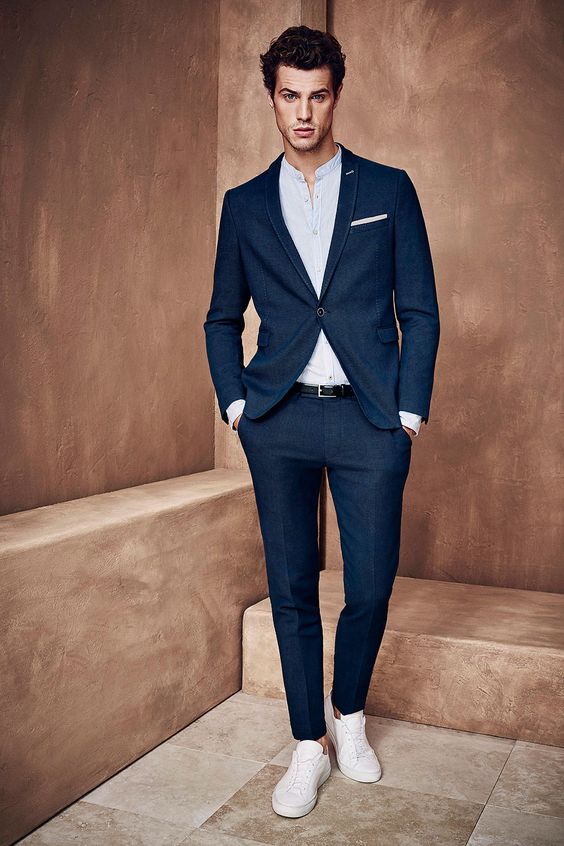 a chic navy suit, a white shirt, no tie and white sneakers with no socks for an elegant modern outfit