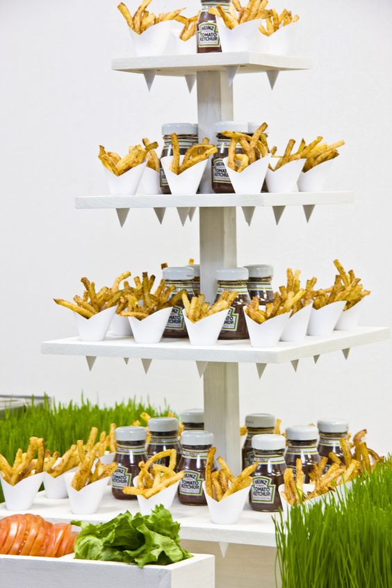 a creative French fry stand with ketchup and some fresh veggies and French fries in paper cones