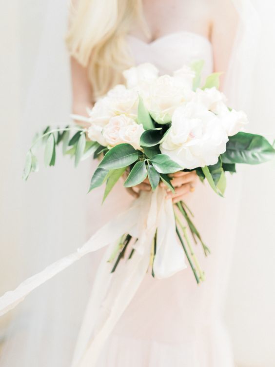 a simple and modern wedding bouquet of blush blooms and some greenery plus matching ribbons