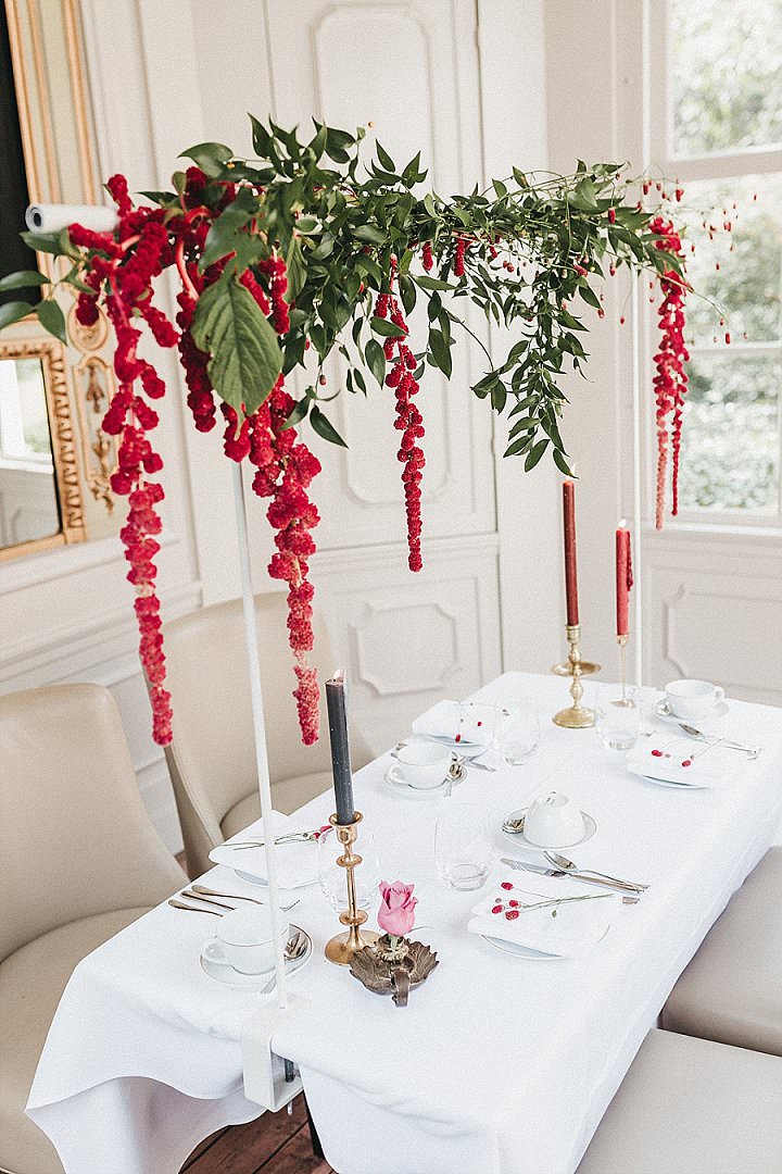 The wedding tablescape was done inside, in the tea house, with crimson blooms and greenery over the table