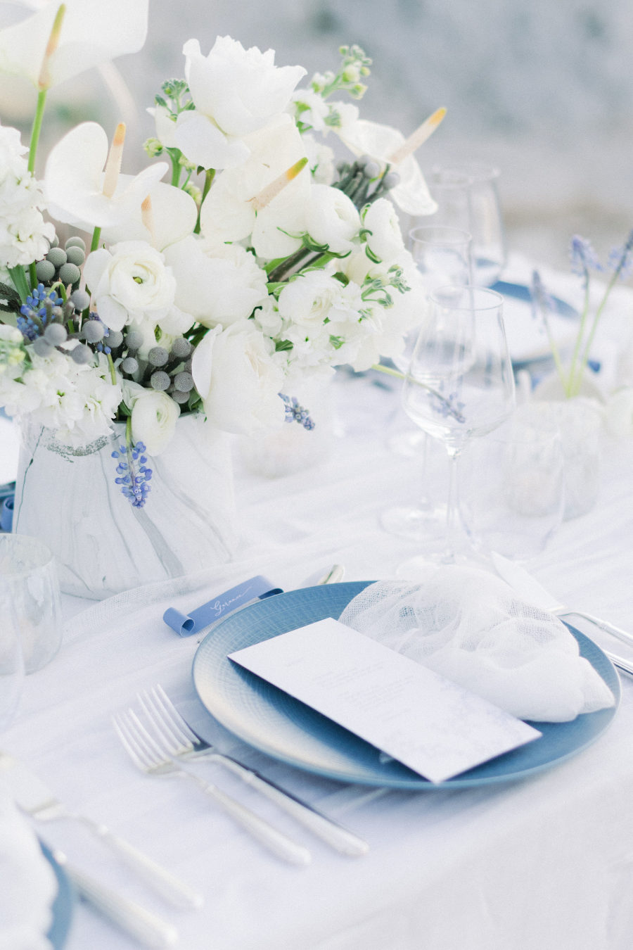 The wedding table was done in white and blues with a lush floral centerpiece, blue chargers and neutrals