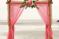 a cute pink wedding arch for a beach wedding