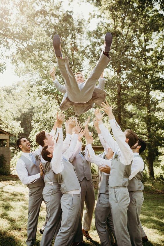 a groom praised by his groomsmen is a fun photo idea that will easily substitute a usual portrait with your friends