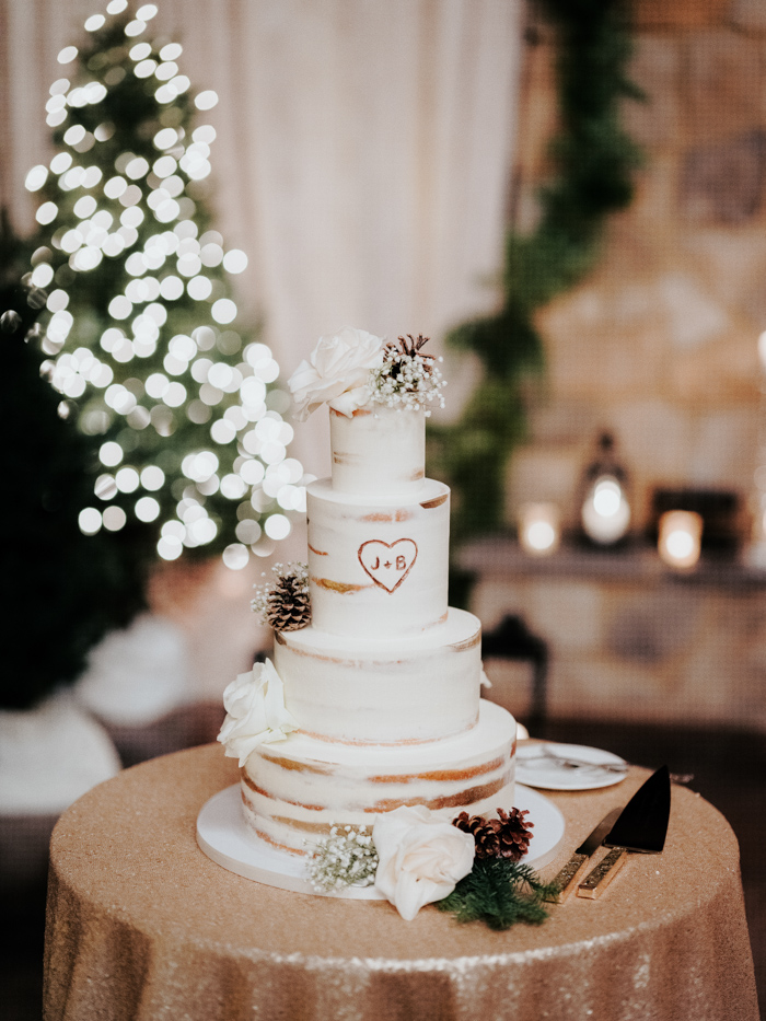The wedding cake was naked and decorated with pinecones, white roses and baby's breath
