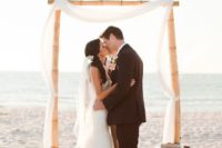 13 a very simple bamboo wedding arch styled only with some airy white fabric is great for a modern beach wedding