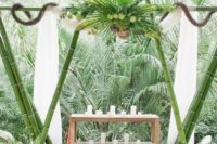 14 a green bamboo wedding arch decorated with tropical leaves and greenery for an African safari wedding