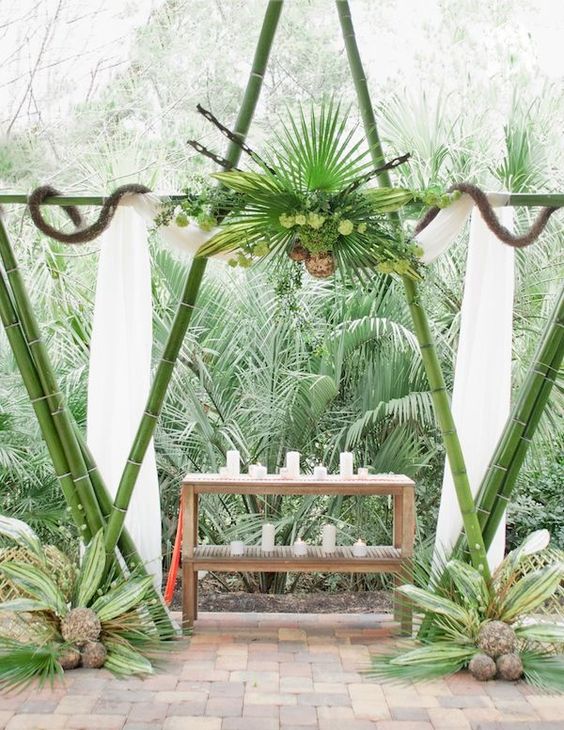 a green bamboo wedding arch decorated with tropical leaves and greenery for an African safari wedding