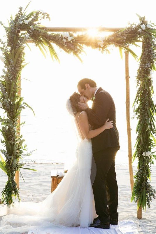 a nice beach wedding arch with lots of greenery