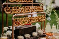 17 a stylish industrial pretzel bar with copper pipes and pretzels on hooks, with dips and veggies