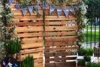 20 a rustic wedding backdrop of pallets, colorful buntings, lush greenery and baskets and potted plants