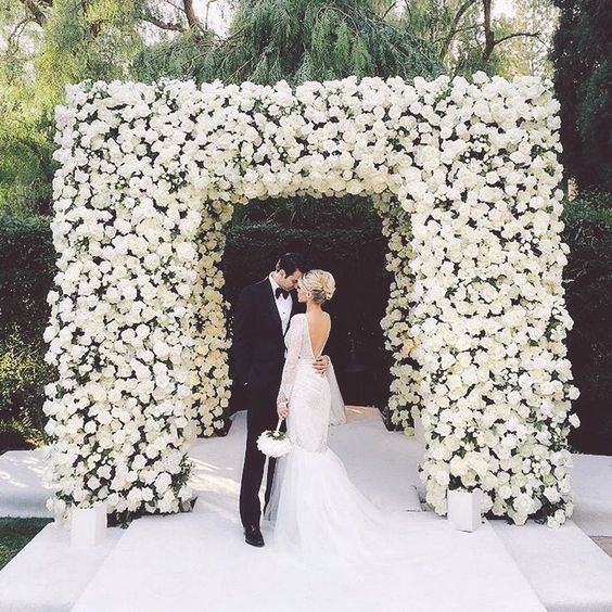 a modern and luxurious wedding chuppah fully covered with white roses is a stunning statement