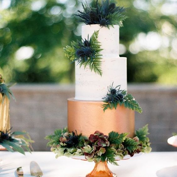 a color block wedding cake with a copper and white layers plus lush tropical greenery